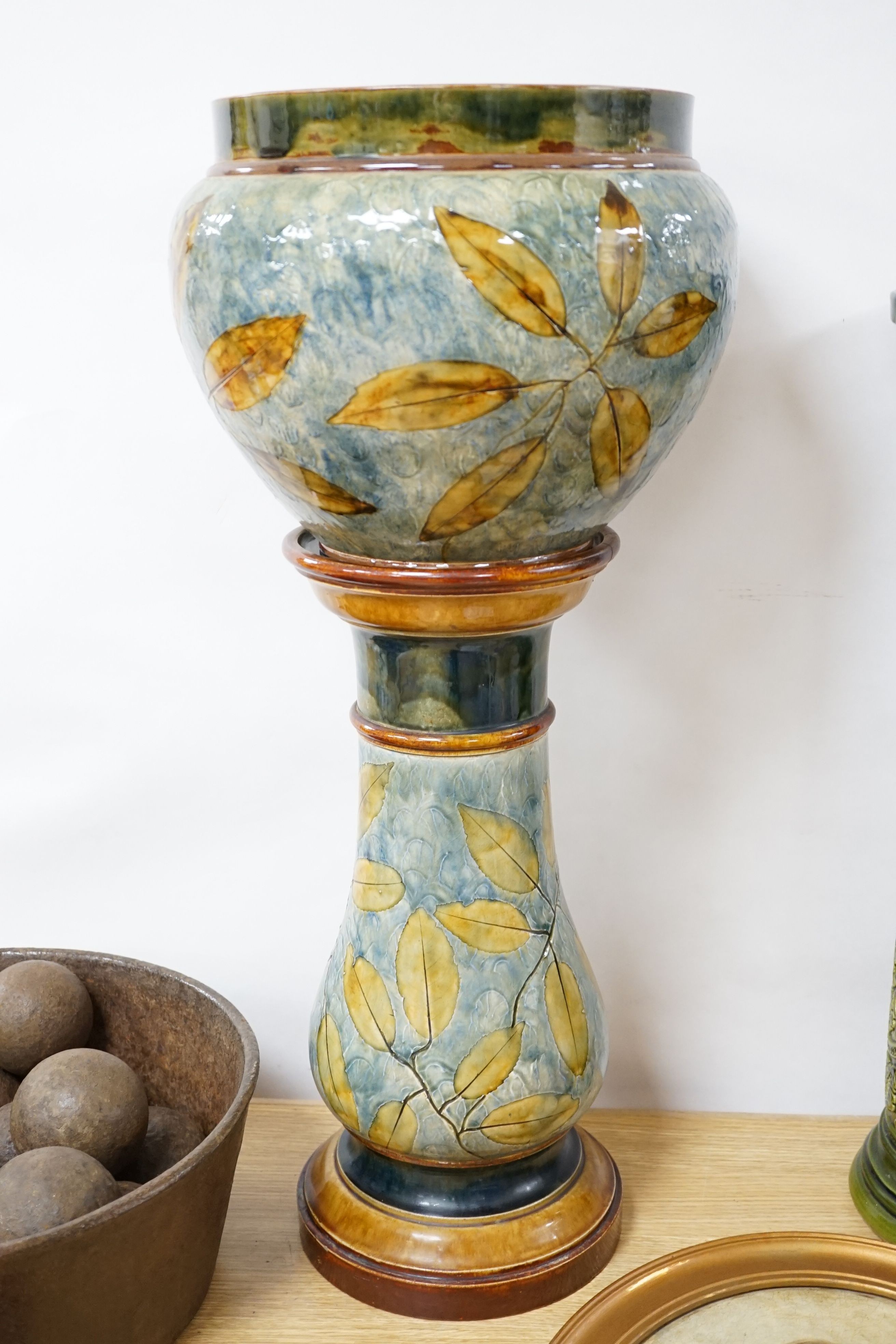 A Doulton, Lambeth Autumnal leaves jardinière on stand, 73cm high and a Burmantofts green glazed stoneware jardiniere stand, 62cm (3)